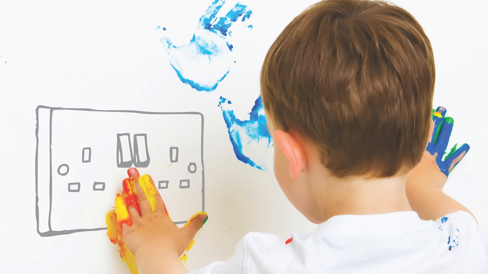 A child with paint on their hands plays with an imaginary power socket