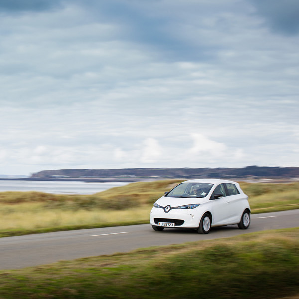 An electric vehicle speeds across the Five Mile Road in St Ouen on a cloudy covered day.