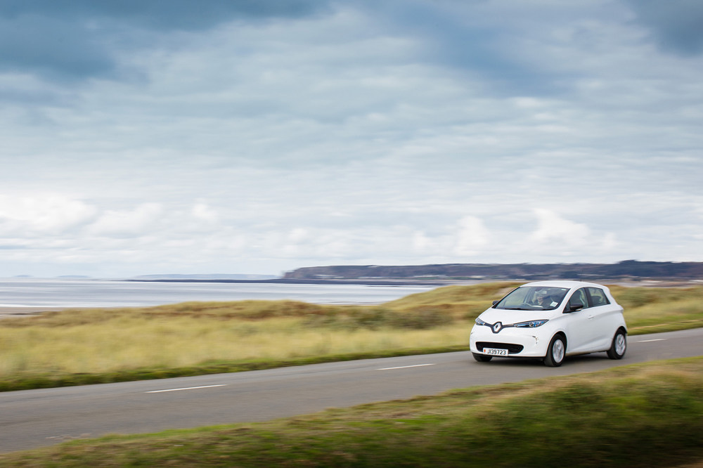 An electric vehicle speeds across the Five Mile Road in St Ouen on a cloudy covered day.