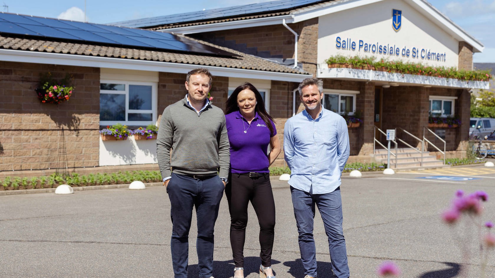 Three people stand outside a building labeled 