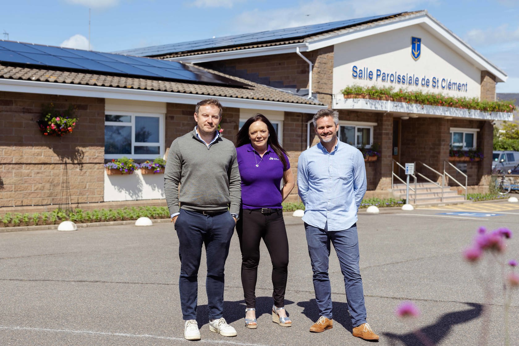 Three people stand outside a building labeled
