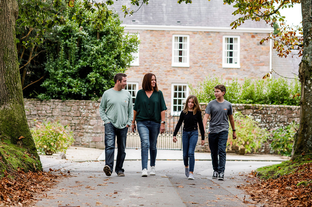 A family walk past a period house in the Jersey countryside.