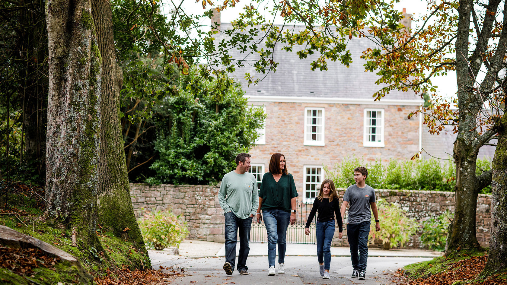 A family walk past a period house in the Jersey countryside.