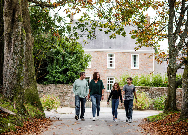 A family walk past a period house in the Jersey countryside.