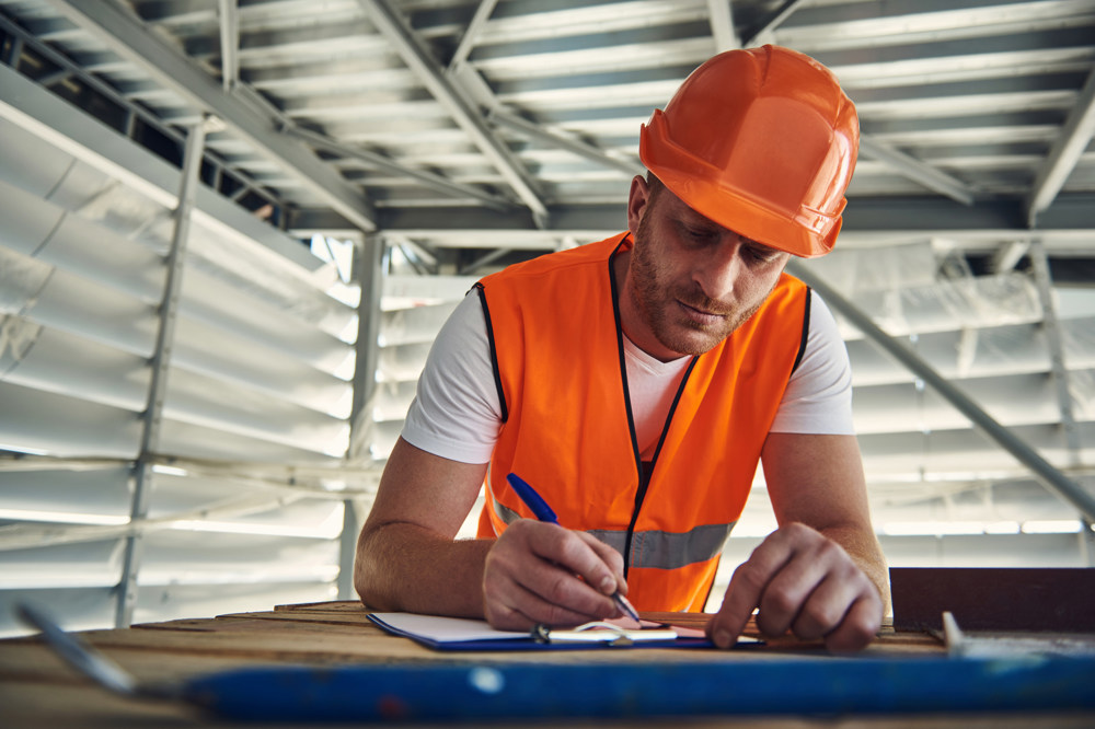 A tradesman completes a form on site.