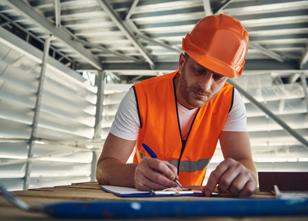 A tradesman completes a form on site.