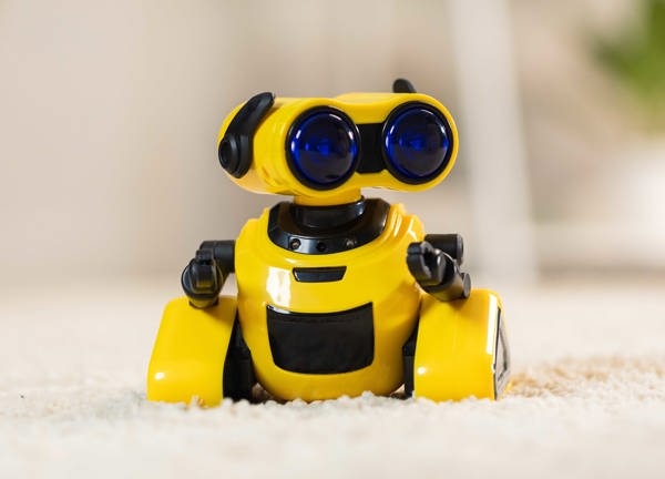 Yellow toy robot sat on a cream carept.