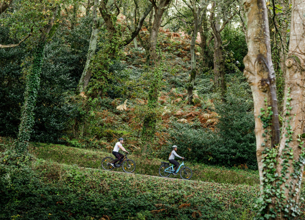 Couple on electric bikes ride down hill