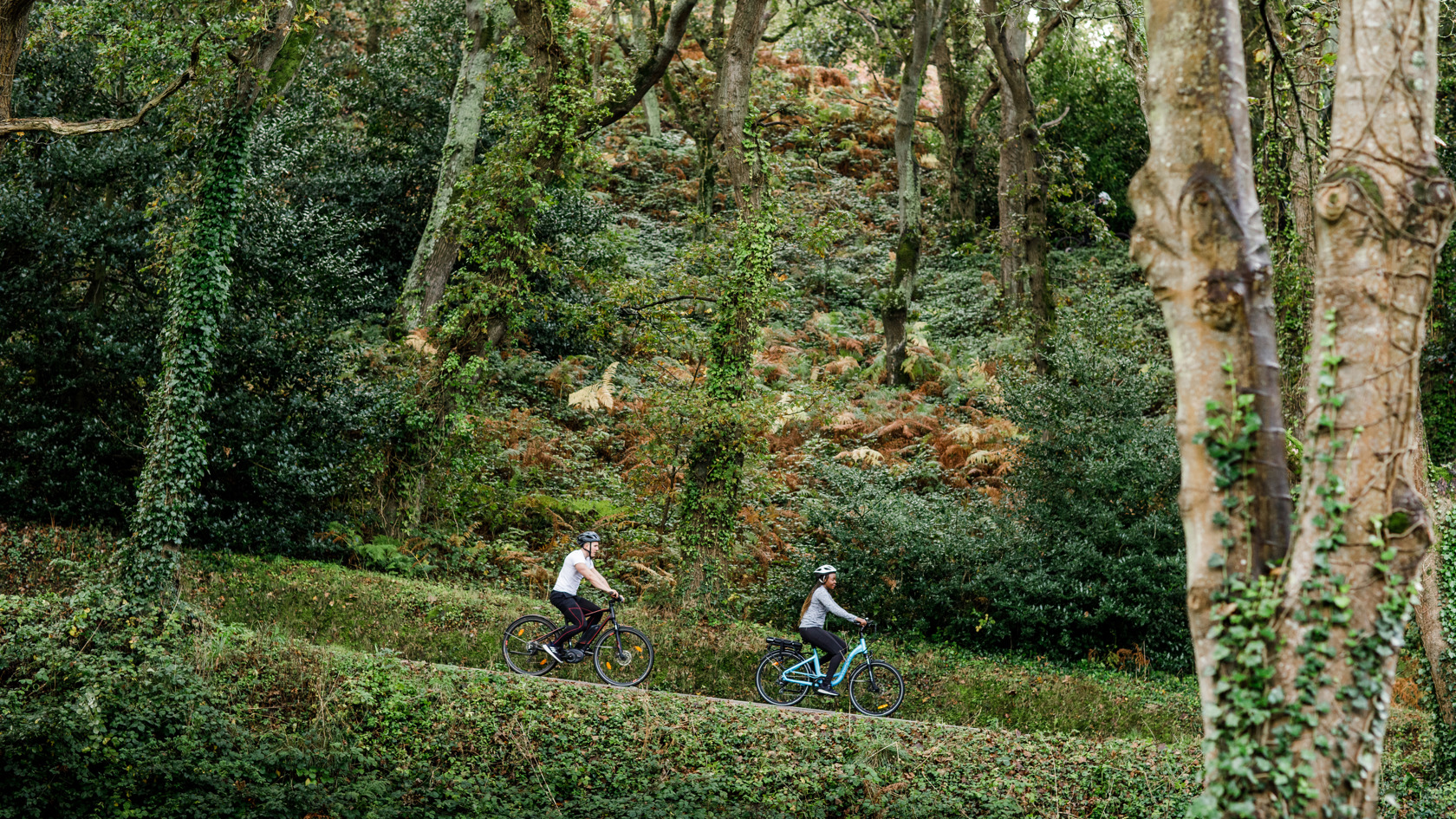 Couple on electric bikes ride down hill