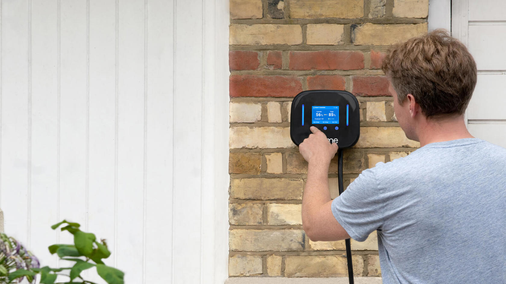Man presses the screen on an Ohme electric vehicle charger