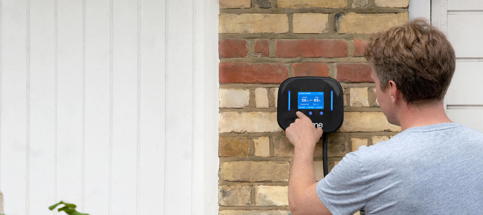 Man presses the screen on an Ohme electric vehicle charger