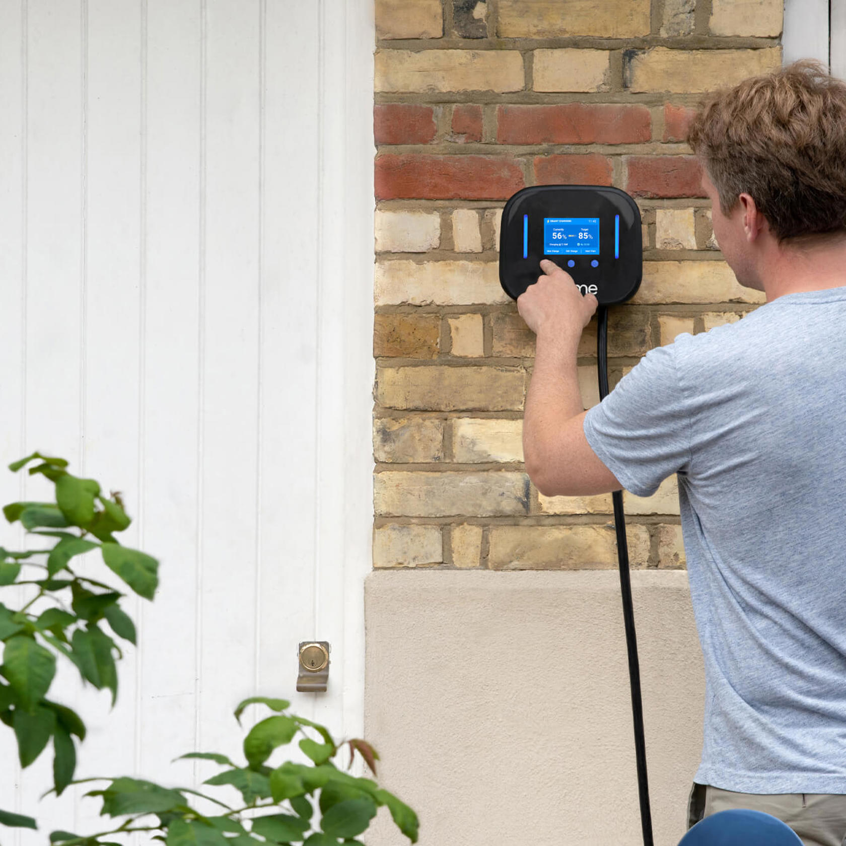 Man presses the screen on an Ohme electric vehicle charger