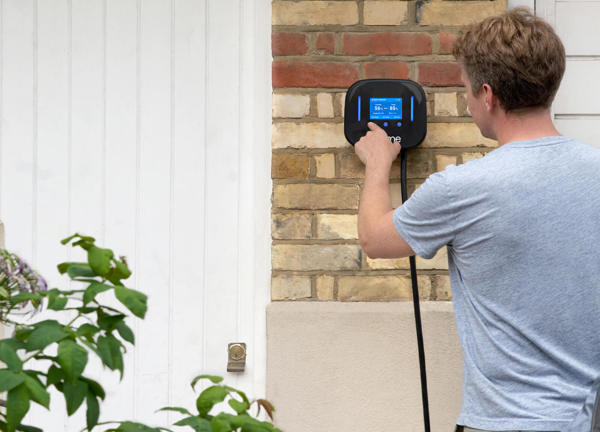 Man presses the screen on an Ohme electric vehicle charger