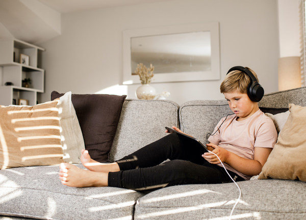Boy uses iPad on couch