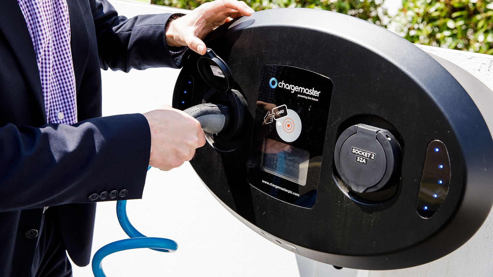 A man in a suit uses the electric vehicle charger at The Powerhouse