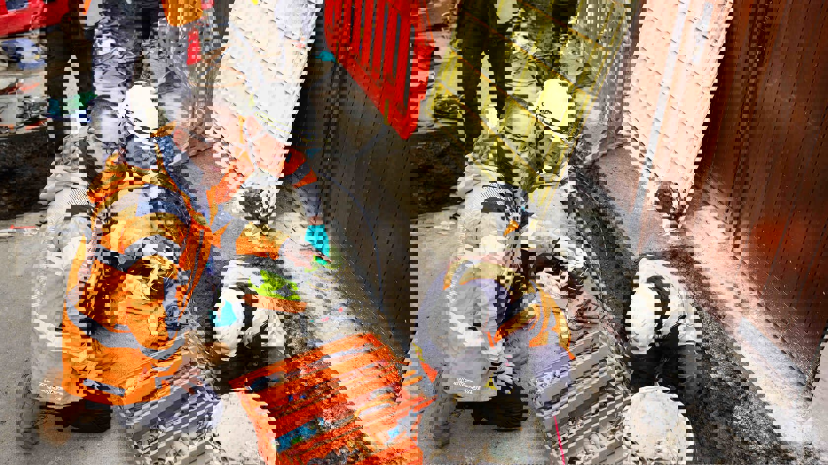 JE employees wearing PPE are inspecting an open pit where a man in PPE is working on an electricty cable