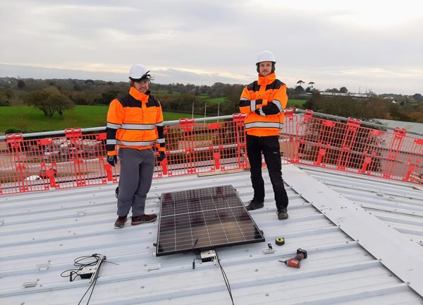 Two members of the Sunworks team begin the Solar PV installation on the roof at Jersey Dairy.