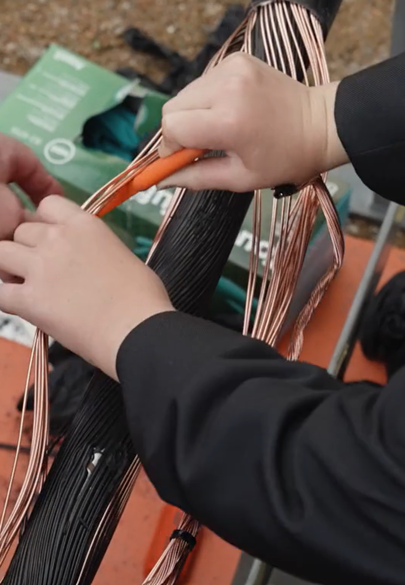 A close up shot of a student being shown how to work on electrical demostration equipment