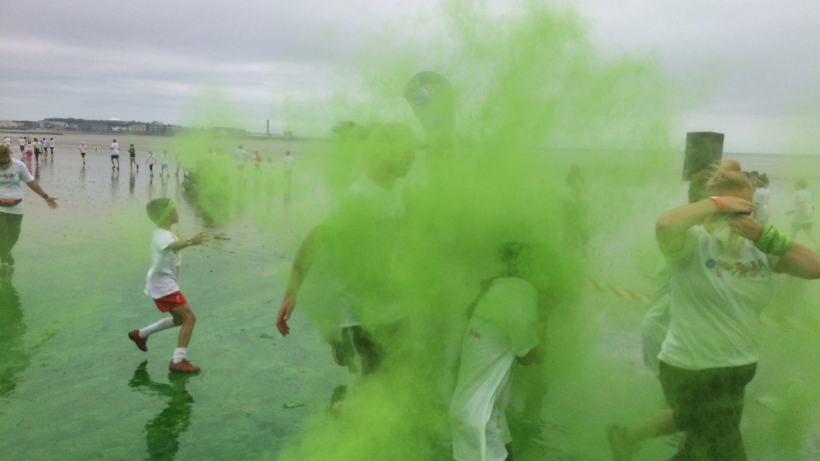 Children throw green paint at each other during the colour run