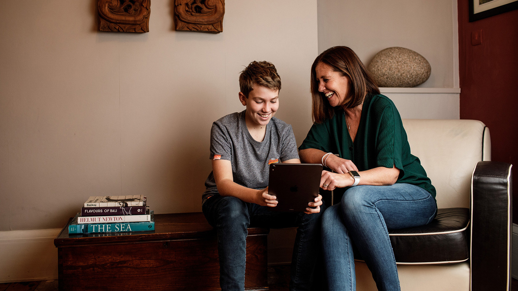 A mother and son laugh together over something they've seen on a tablet.