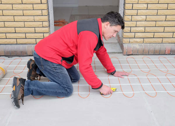An electrician installs electric underfloor heating.