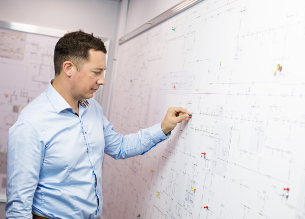 Ashley Mariner, a Jersey Electricity Engineer inspects a wall of drawings.