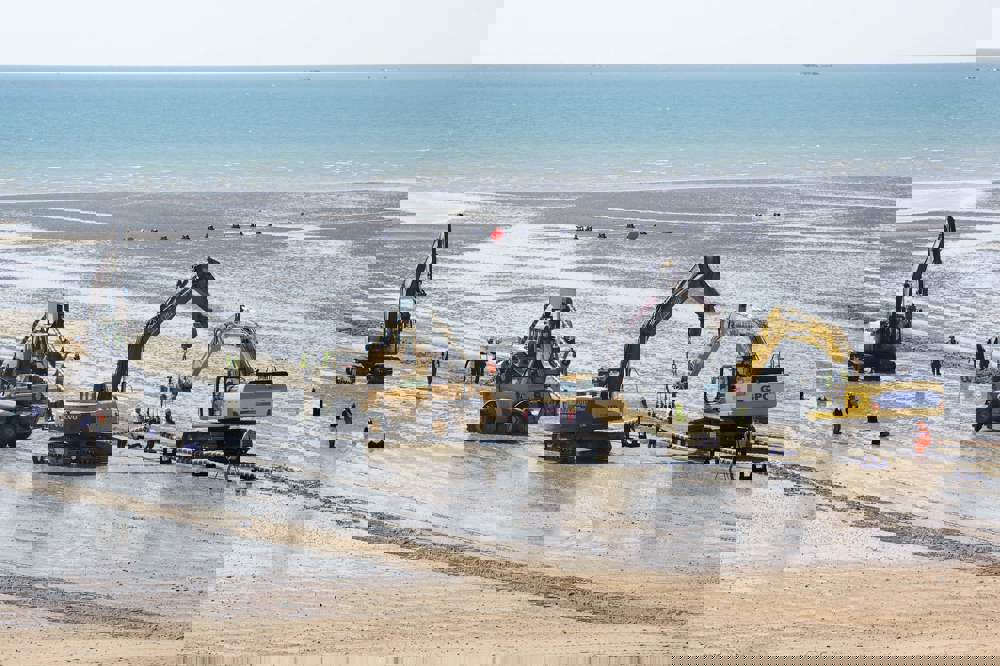 Excavators on the beach lift the Normandie 3 subsea cable into place.