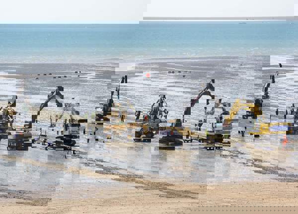 Excavators on the beach lift the Normandie 3 subsea cable into place.
