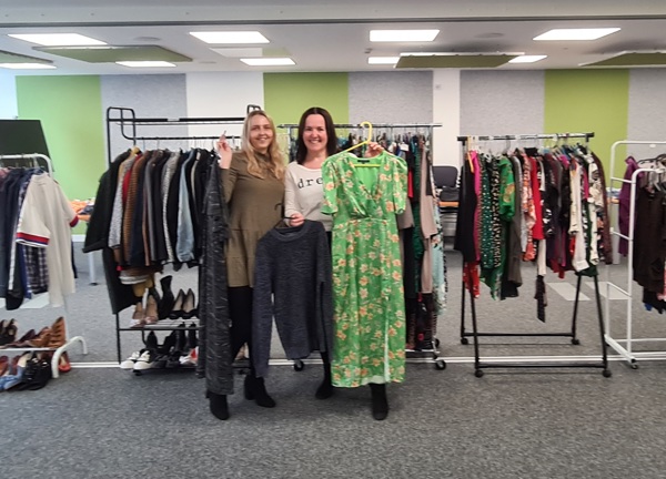 Image of Chloe Dunderdale and Sarah Le Gresley at the JE clothes swap. Behind them are rails packed full of donated clothes