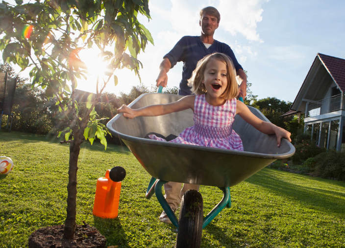 Father pushing daughter in a wheelbarrow