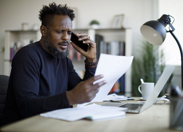 Man looks at a bill whilst on the phone