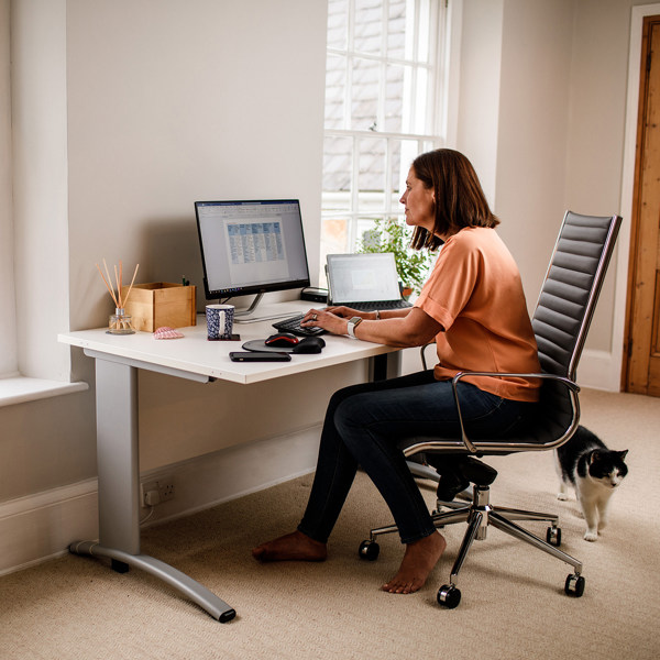 A woman uses a computer in a cosy looking home office.