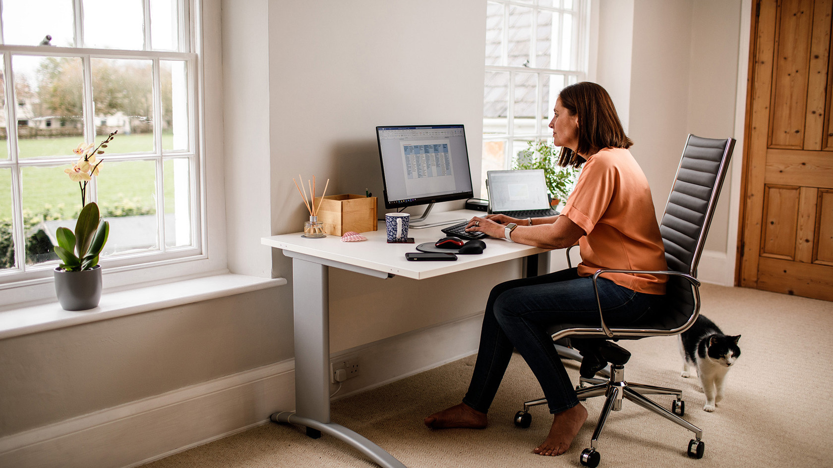 A woman uses a computer in a cosy looking home office.