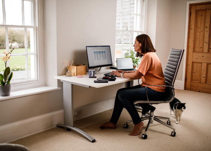 A woman uses a computer in a cosy looking home office.