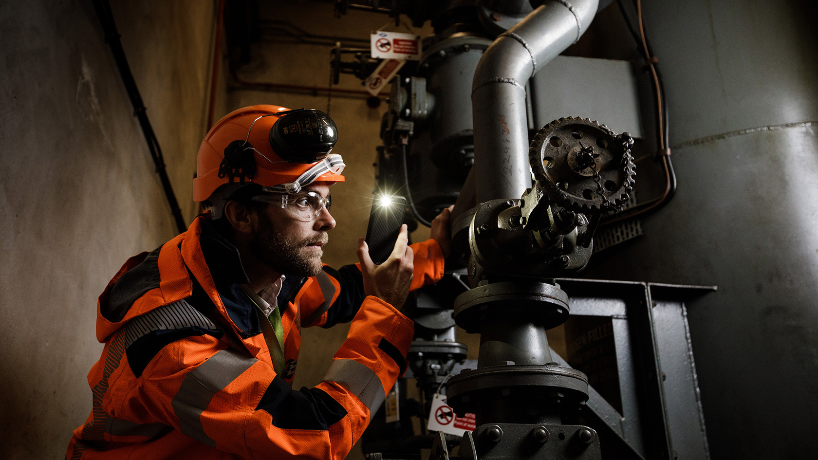 Sam Boleat uses his phone light to inspect a piece of equipment. 
