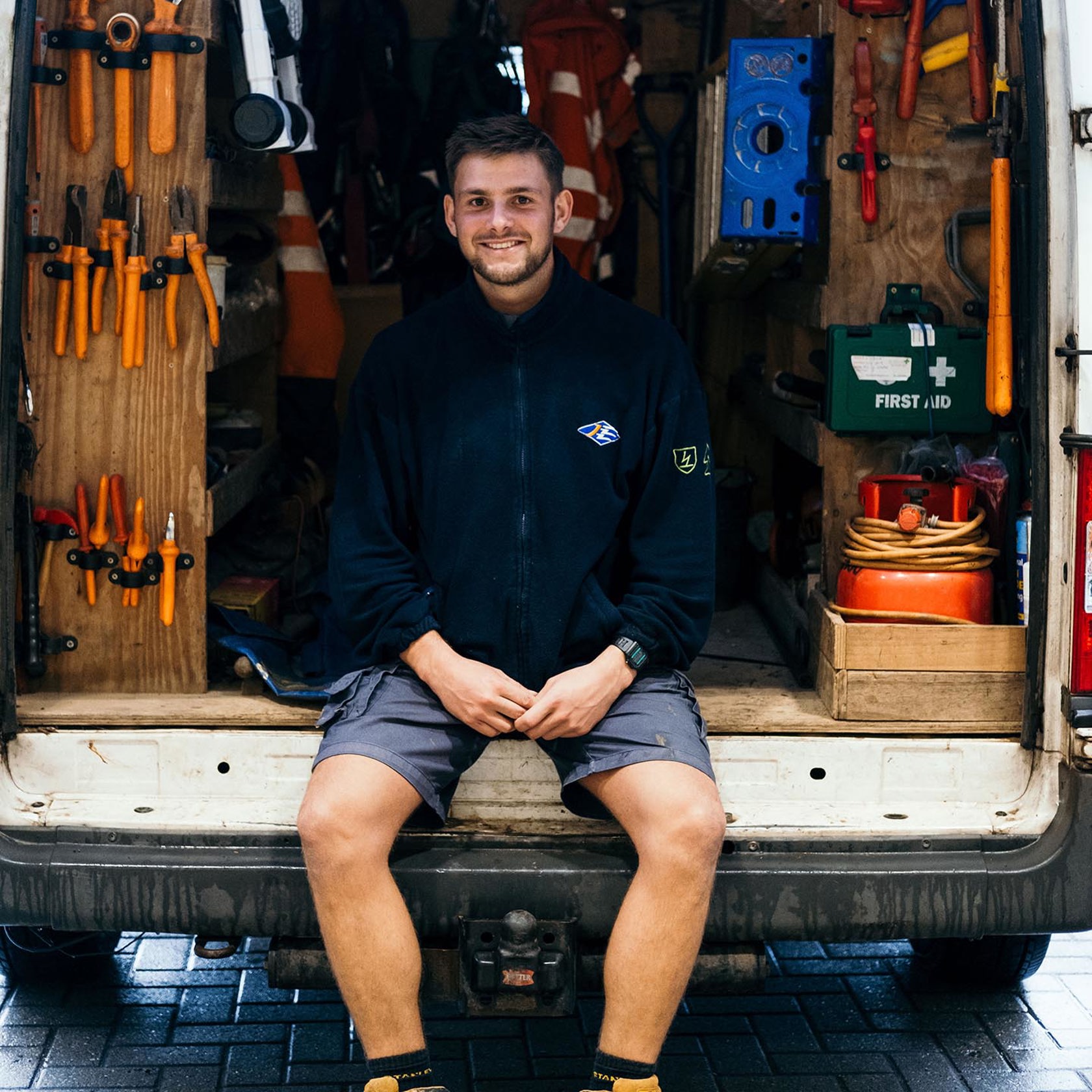 A Jersey Electricity Apprentice sits in the back of a van.