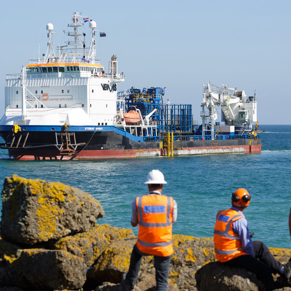 Three members of the Normandie 1 project team watch as Stemat arrives in Jersey.