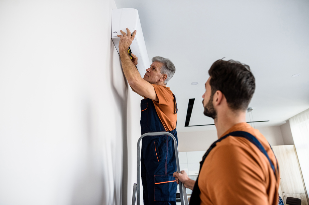 Two men install a home heat pump