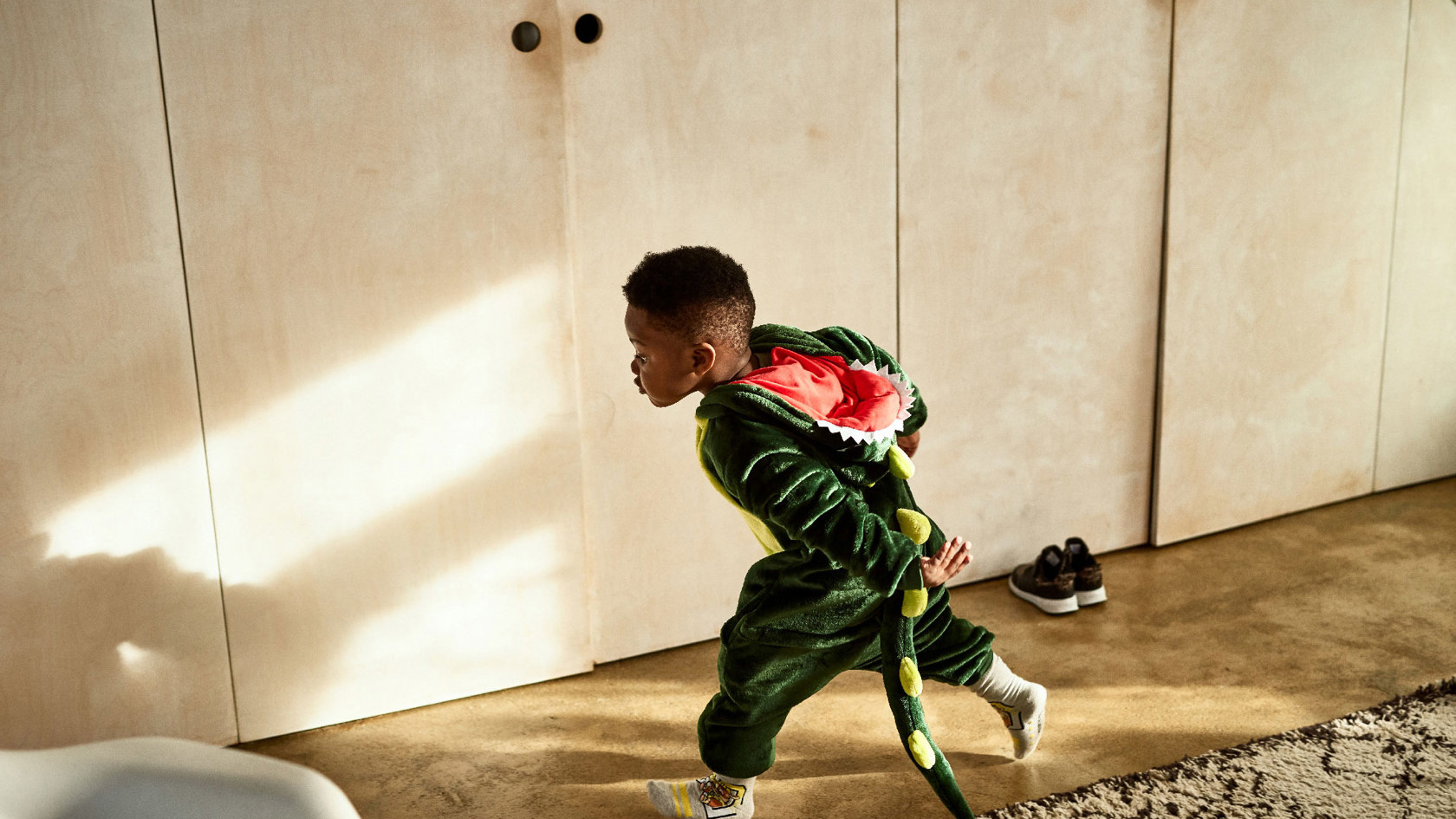 A boy running through a house in an aligator costume