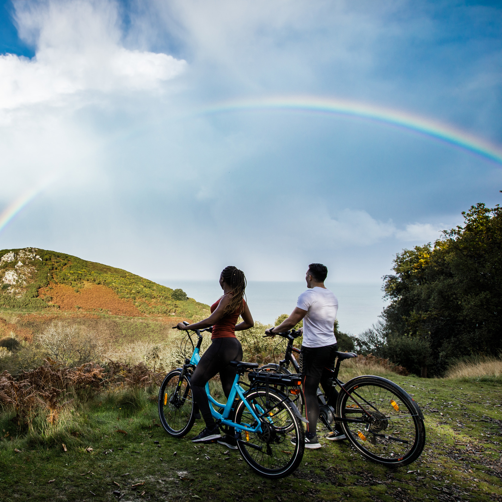 Couple On Bikes With Rainbow