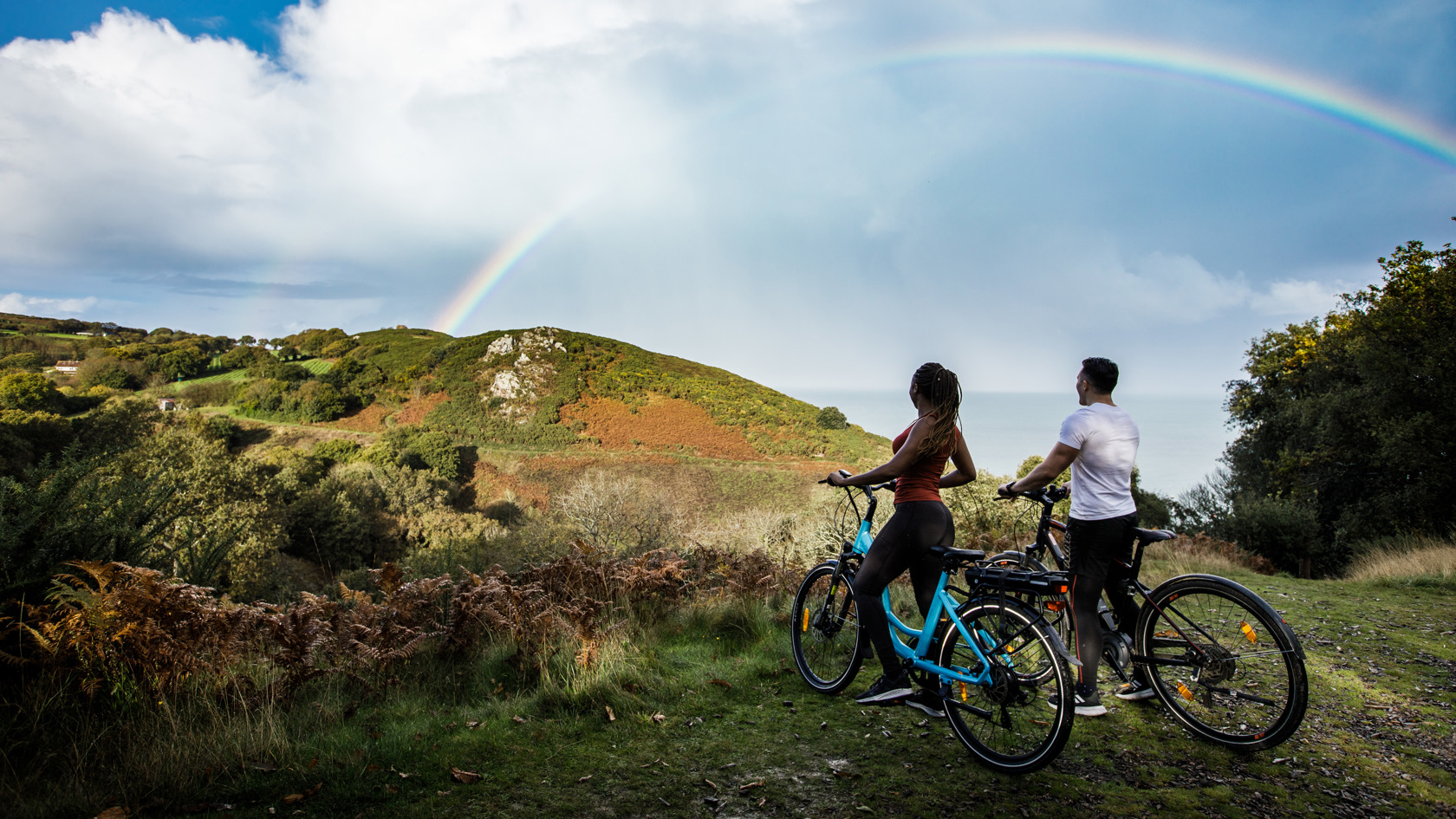 Couple On Bikes With Rainbow