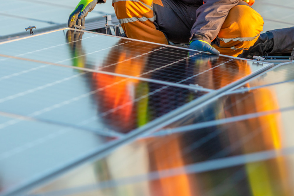 Man installing solar panels on roof