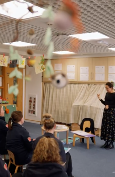 A lady is teaching in front of a group of support workers teaching them Makaton Signing.