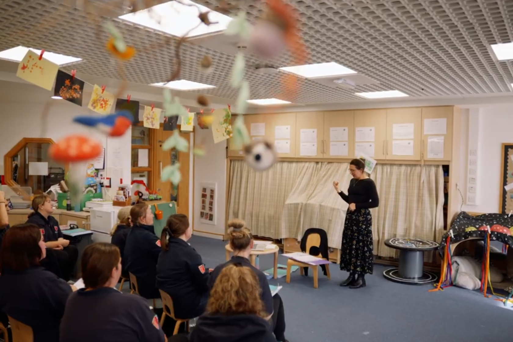 A lady is teaching in front of a group of support workers teaching them Makaton Signing.