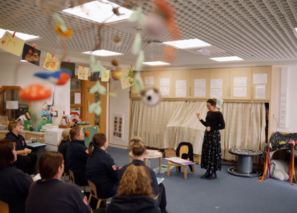 A lady is teaching in front of a group of support workers teaching them Makaton Signing.