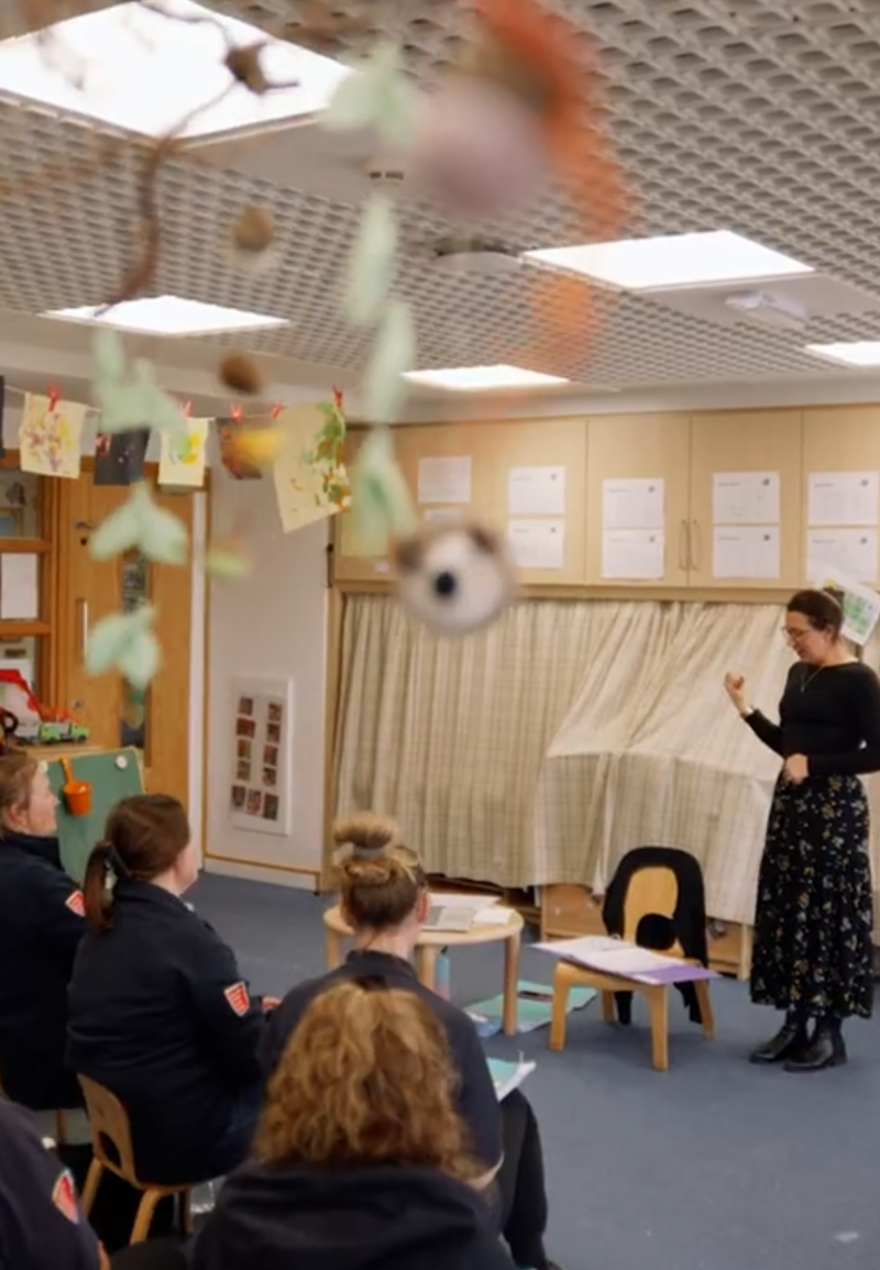 A lady is teaching in front of a group of support workers teaching them Makaton Signing.