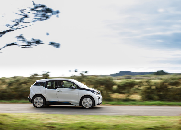 A white electric car drives along a road in Jersey.