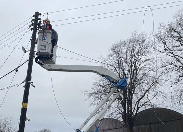 A JE linesman in PPE fixing an overhead line in storm Éowyn, Norther Ireland