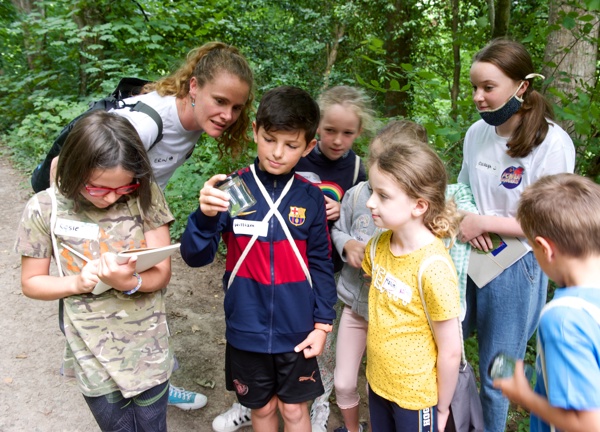 Erin and seven children inspect a jar of bugs