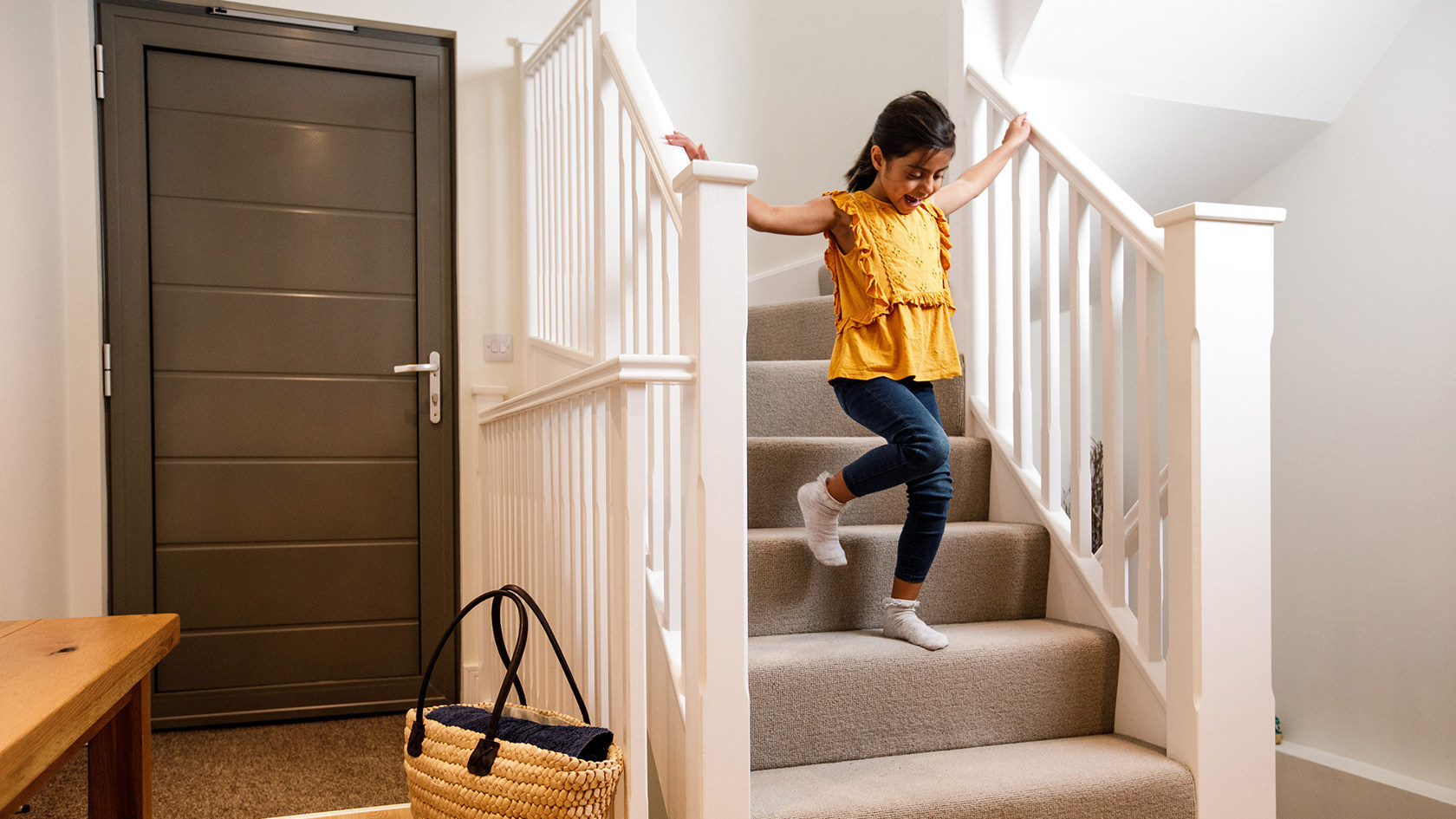 A young girl runs down the stairs in a modern electric home.